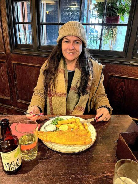 Mulher em um pub em Londres comendo fish and chips